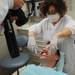 Dental Assistant Jean Curmi uses "fish hooks" to hold Jean-Claude Soloman's mouth open as he is photographed during a step in the process of installing his new teeth. Melanie Maxwell I AnnArbor.com